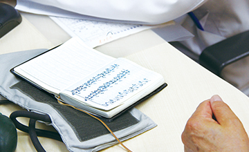 患者さんが机の上に開いた、血圧の数値を書き留めたノートの画像。