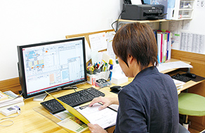 オフィスでスケジュールやカルテのチェックを行う石賀先生の画像。