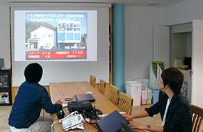 石賀先生のよる研修医への在宅医療についての講義の画像。プロジェクターとPCを使って説明しています。